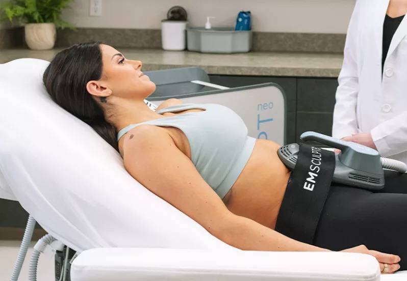 Emsculpt Neo treatment in Morristown, NJ: patient lying on a treatment table with the applicator strapped over her abdomen